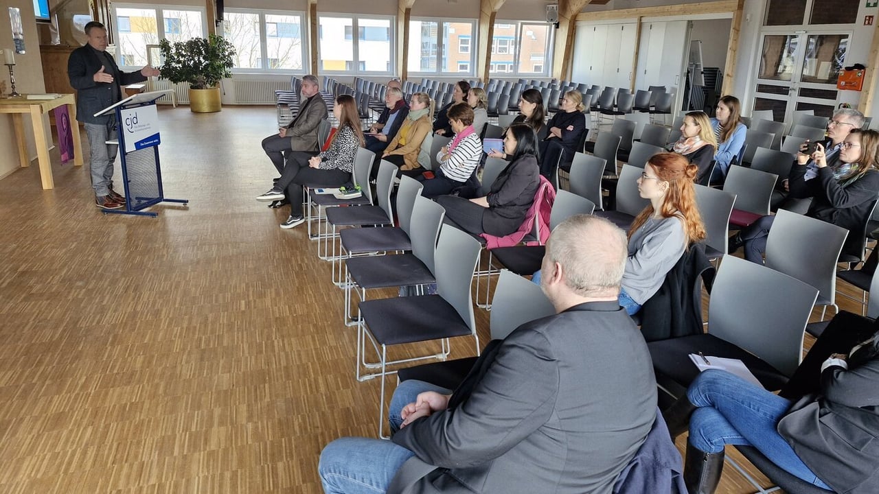 Das Foto zeigt die Teilnehmer*innen in einer Aula